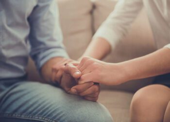 Cropped image of beautiful female psychologist holding her client's hands during the seance