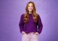8 Mart Dünya Kadınlar Günü: Kadın Gücü 2 Optimistic attractive ginger girl in 20s wearing purple sweater standing ready and energized over violer background smiling friendly and confident at camera, showing readiness to have fun.