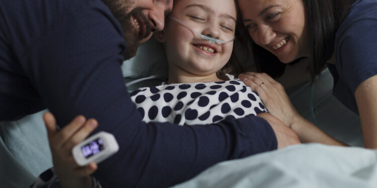 Kanser: Hasta ve Aile İlişkileri Nasıl Güçlendirilir? 1 Loving parents hugging sick daughter resting in healthcare clinic pediatrics ward. Happy ill little girl hugged by caring mother and father while sitting with her on patient bed.