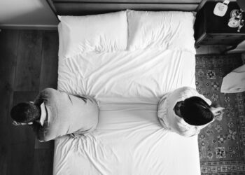 Interracial couple sitting back to back on the bed