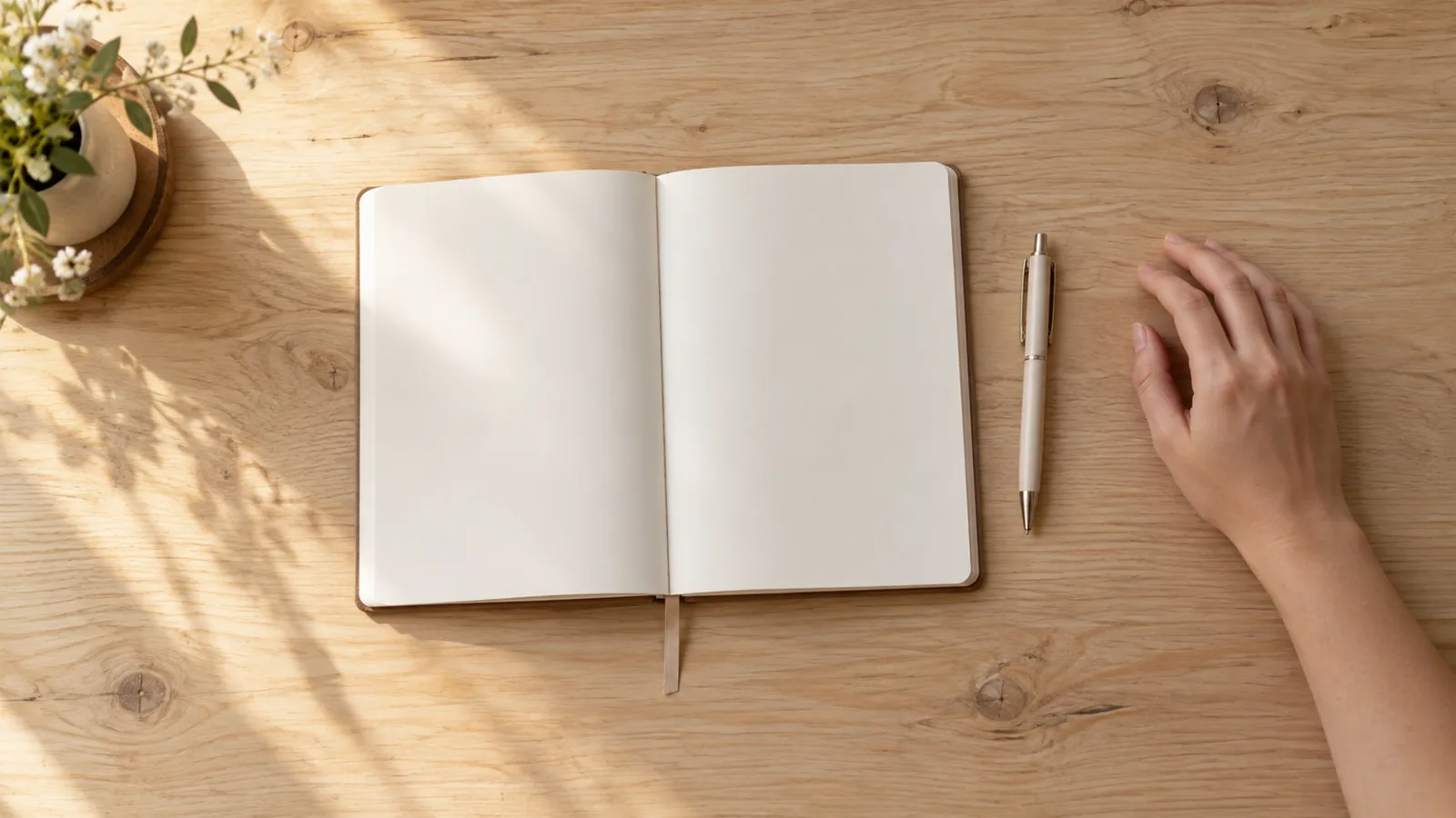 Açık bir defter ve kalemin durduğu sade bir masa